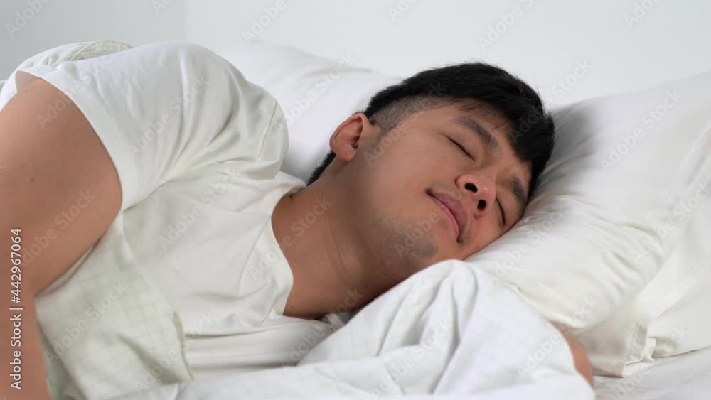 Happy Young Asian man sleep in comfortable bed in the morning.