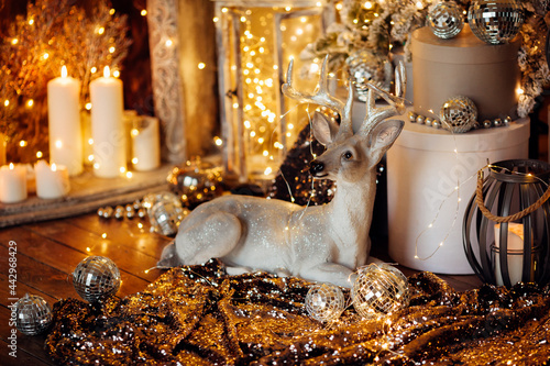 warm and cozy evening in Christmas room interior design,Xmas tree decorated by lights presents gifts,toys, deer,candles, lanterns, garland lighting indoors fireplace.holiday living room.magic New year