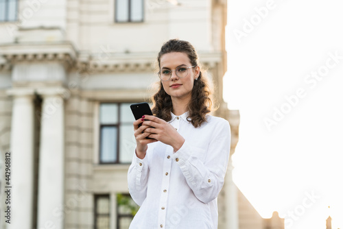 An attractive young woman walking in the city center, texting and laughing. Woman entrepreneur taking a break from work checking her cell phone.