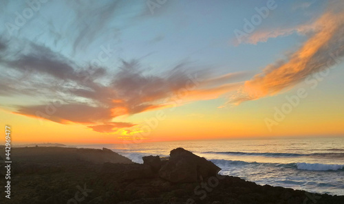 Scenic view of a rocky coast facing the Atlantic Ocean during a beautiful sunset. Romantic evening with a wonderful cloudy sky over the sea.