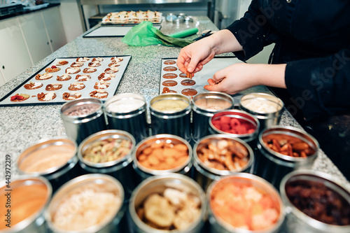 Chef woman preparing chocolate desserts in trays inside kitchen restaurant - Focus on hands