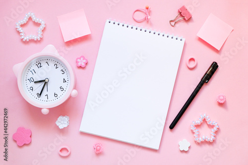 Blank notepad with pen and pink alarm clock with cat ears on pink background. Good morning concept