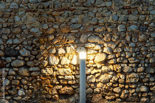 Stone wall illuminated with a modern lamp. 