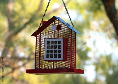 Red House Barn shaped suet bird feeder with seed hanging in the yard  © Kella
