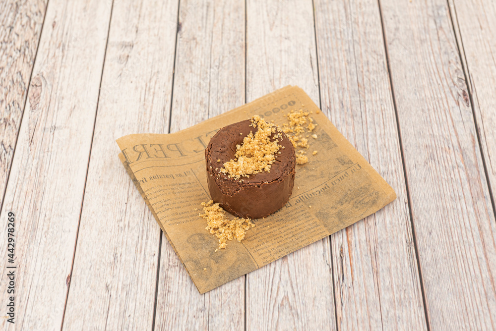 One serving chocolate cake with biscuit sand on top on a light wooden table One serving chocolate cake with biscuit sand on top on a light wooden table