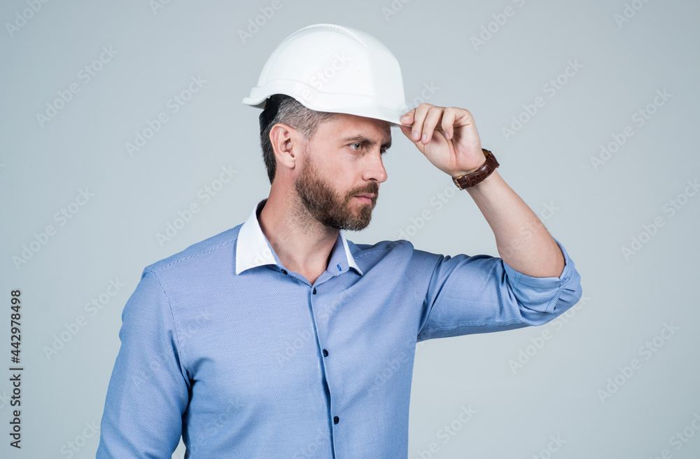 mature bearded businessman in helmet. confident guy pointing finger on copy space.
