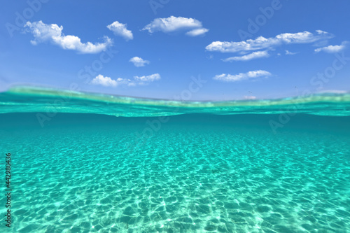 Split underwater photo of exotic island paradise bay with crystal clear emerald sandy beach