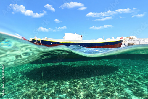 Fototapeta Naklejka Na Ścianę i Meble -  Sea level and underwater split photo of traditional wooden fishing boat anchored in Aegean island port with emerald crystal clear sea