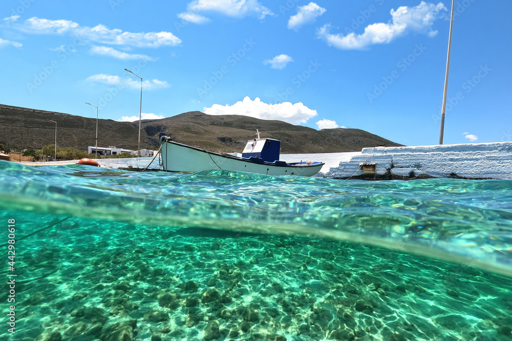 Sea level and underwater split photo of traditional wooden fishing boat anchored in Aegean island port with emerald crystal clear sea