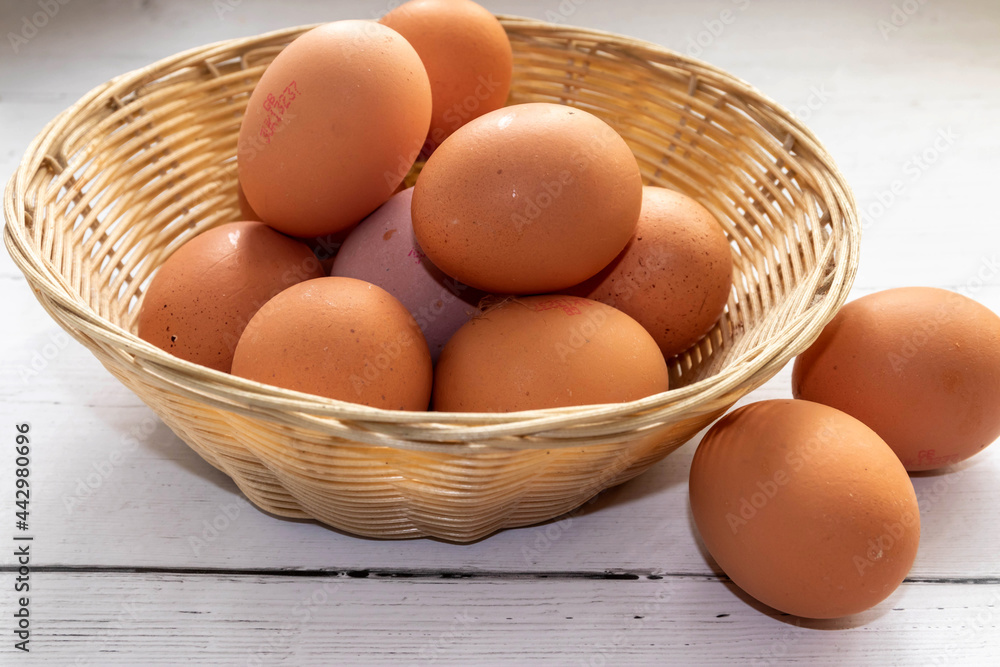 Fresh Eggs in a Basket, with two on the side on a white kitchen counter top Fresh Eggs in a Basket, with two on the side on a white kitchen counter top