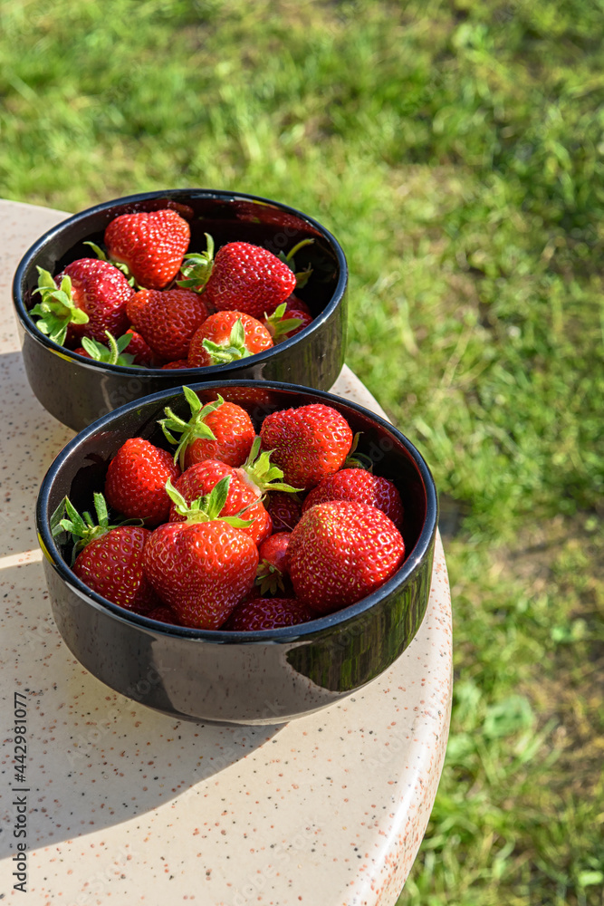 Fresh strawberries in a black plate on a granite table Fresh strawberries in a black plate on a granite table