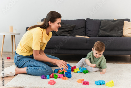 Smiling mother playing building blocks in living room