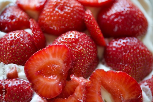 Sweet red strawberries on whipped cream on top of cake. Macro much.
