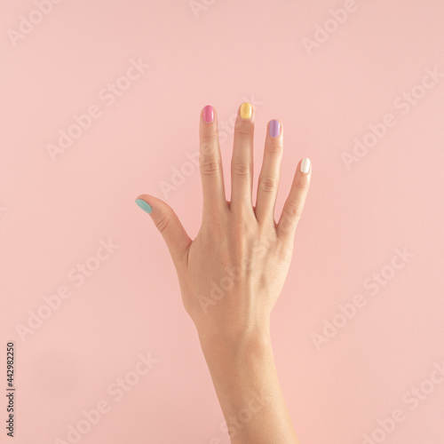 women hands with colorful nails on the pastel pink background. copy space.  summer modern tropical abstract art with female hand. minimal background idea with number five
