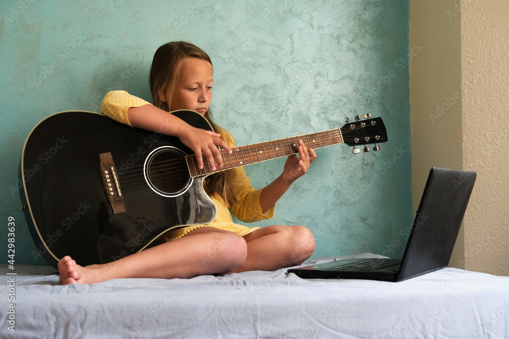 Obraz premium a little girl is learning to play the guitar