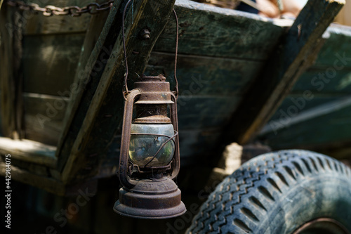Old rusty kerosene lamp hanging on vintage horse cart in country side