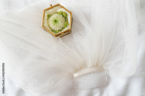 Wedding rings of the bride and groom in a elegant golden glass box lying on the bride's veil