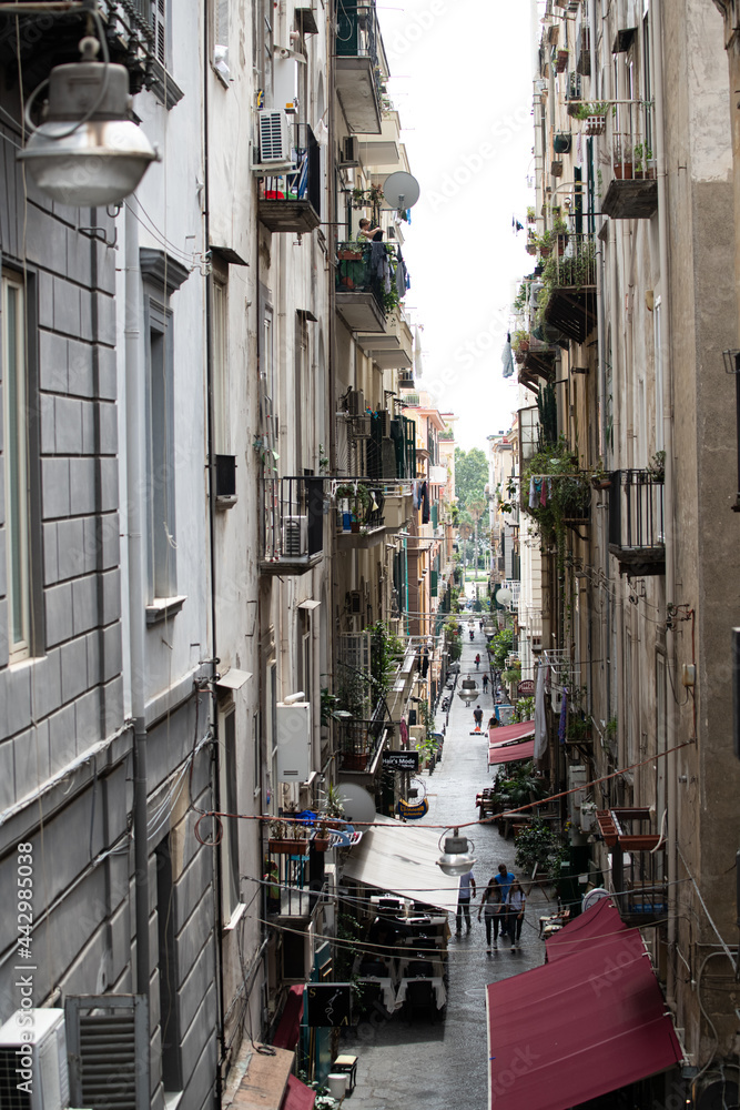Narrow street in Naples Italy. Typical Italian small street in Sicily.  Flowers growing on small cozy balconies