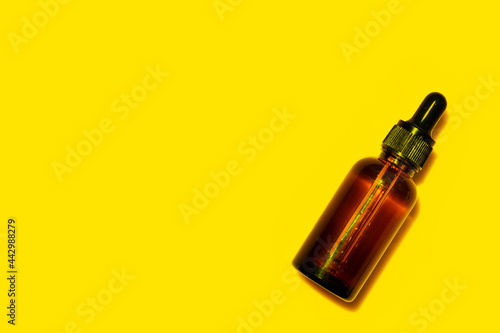 Brown bottle with essential oil on yellow background