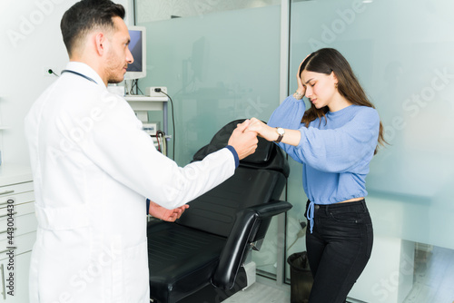 Physician helping a latin woman feeling faint