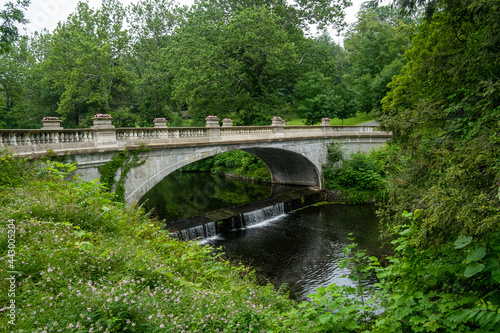 Hyde Park, NY - USA - July 1, 2021: View of the White Bridge, spanning Crum Elbow Creek. It has an elegant arch, ornamented balustrade, and recessed panels. Located at the Vanderbilt mansion.