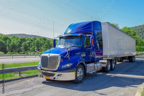 The blue truck and white container in transport industry is stop and rest on high way