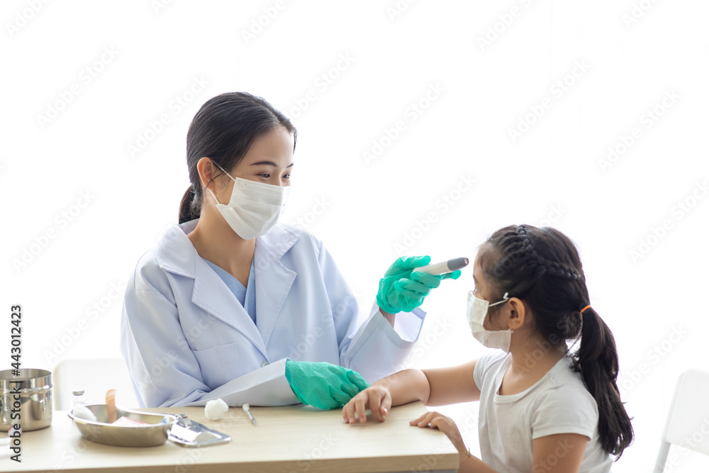Asian female doctor measuring temperature of asian girl with infrared temperature measurement or thermometer at hospital Asian female doctor measuring temperature of asian girl with infrared temperature measurement or thermometer at hospital