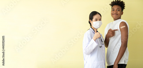 portrait asian woman doctor and black man show thumb up or good sign after injection vaccine . vaccinated against coronavirus in hospital photo