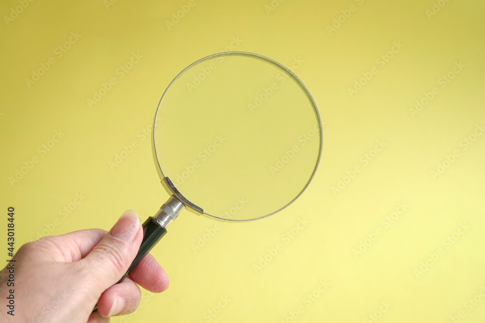 Hand holding magnifying glass. On yellow background. Copy space. Hand holding magnifying glass. On yellow background. Copy space.
