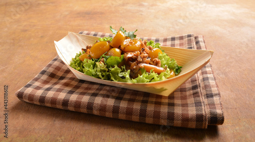 asian hakka traditional cuisine snack menu stir fried abacus ball with minced meat and mushroom in small paper bowl on wood table (suan pan zi) photo