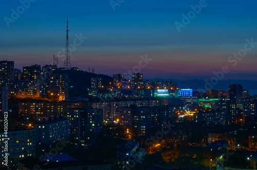 Aerial view of the night city of Vladivostok, Russia. TV tower on a hill, sea bay and mountain range. © Алексей Игнатов