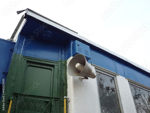 Old train car with a loudspeaker, painted in blue, green and white