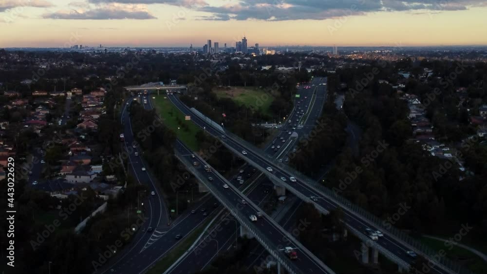 Drone Aerial of Motorway Intersection with Cars and Downtown in the background at Sunset. North West Sydney Australia Drone Aerial of Motorway Intersection with Cars and Downtown in the background at Sunset. North West Sydney Australia