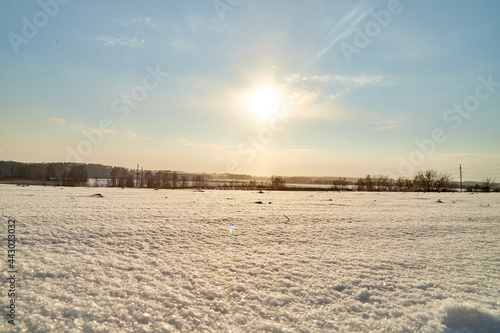 Field  meadow and grass with snow and cold sun on foggy cloudy sky. Beautiful winter landscape. Winter morning  day or evening