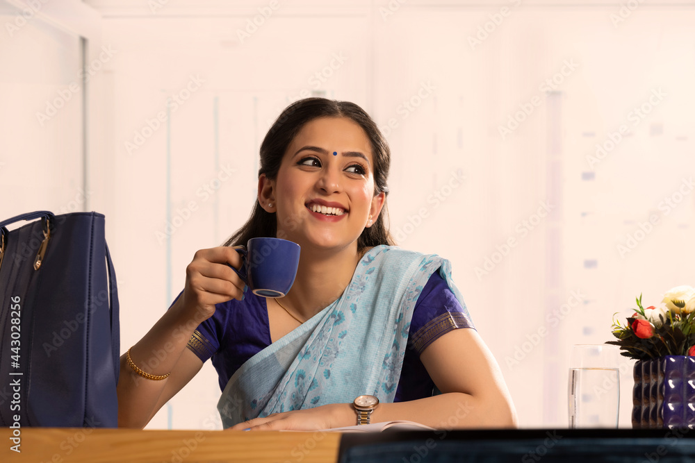 A woman sitting in a room holding a cup. A woman sitting in a room holding a cup.