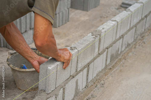 industrial bricklayer installing brick blocks on construction site, selective focus