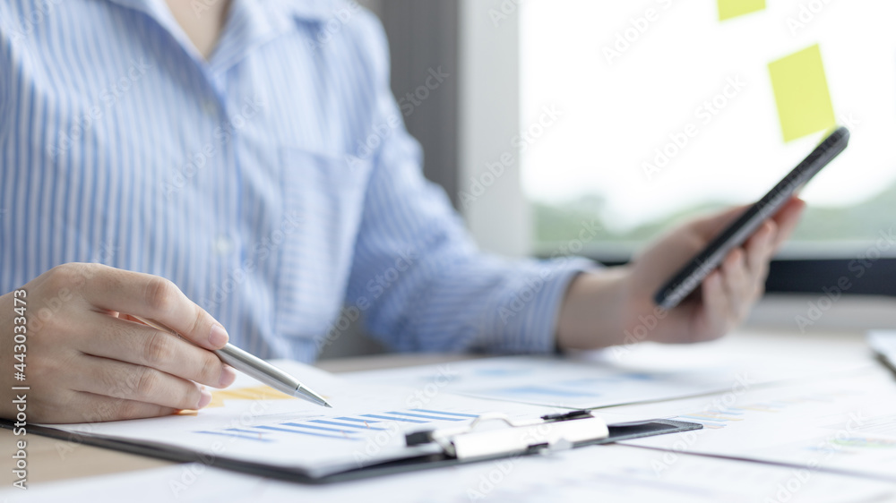 Businessman uses a mobile phone to examine financial data and analyze company growth graphs, Use of smartphone technology in work, Earnings Insights Graph, Finance, Accounting, Tax system, Vat. Businessman uses a mobile phone to examine financial data and analyze company growth graphs, Use of smartphone technology in work, Earnings Insights Graph, Finance, Accounting, Tax system, Vat.