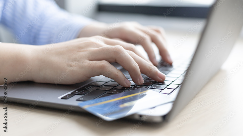 Woman's finger presses a keyboard and holds a credit card to register for payment or online transactions, Financial transactions and Internet security, Shopping online and banking online concept. Woman's finger presses a keyboard and holds a credit card to register for payment or online transactions, Financial transactions and Internet security, Shopping online and banking online concept.