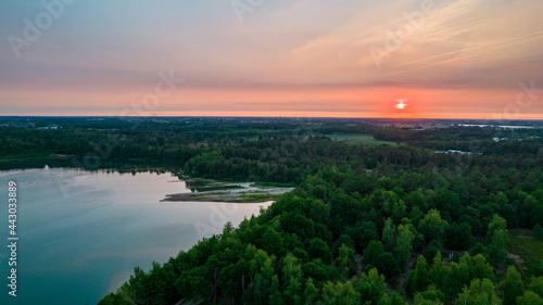 Aerial view of a beautiful and dramatic sunset over a forest lake reflected in the water, landscape drone shot. Blakheide, Beerse, Belgium. High quality photo © Bjorn B