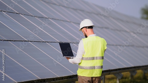 Engineer working use laptop stand near solar batteries construction renewable power worker man technology modern electricity energy slow motion