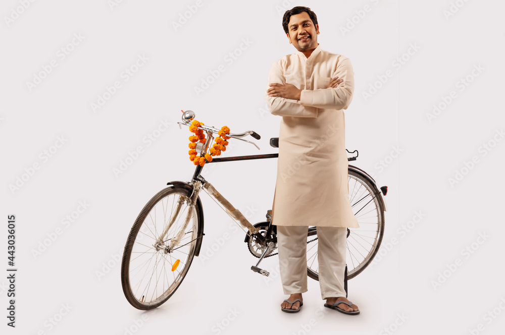 A RURAL MAN CONFIDENTLY POSING WHILE STANDING WITH NEW BICYCLE - obrazy, fototapety, plakaty 