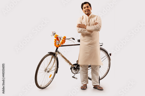 A RURAL MAN CONFIDENTLY POSING WHILE STANDING WITH NEW BICYCLE
