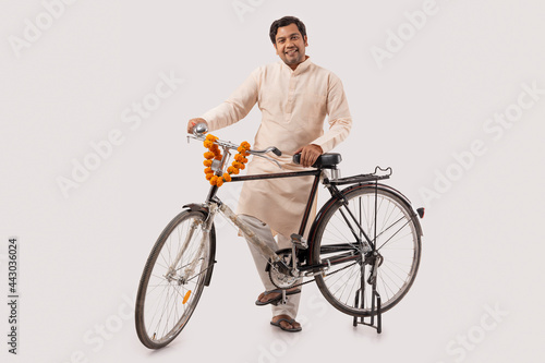 A HAPPY RURAL MAN STANDING WITH BICYCLE AND POSING