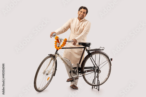 A RURAL MAN POSING HAPPILY WHILE HOLDING NEW BICYCLE