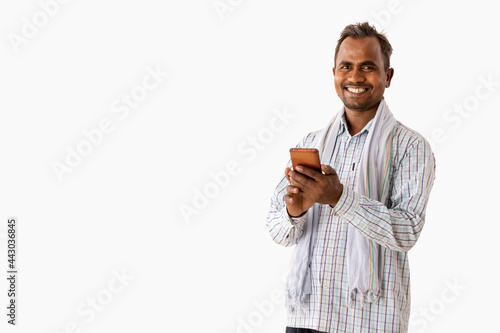 A HAPPY LABOURER LOOKING AT CAMERA WHILE USING MOBILE PHONE