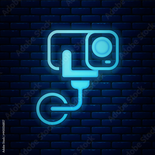 Glowing neon Security camera icon isolated on brick wall background. Vector