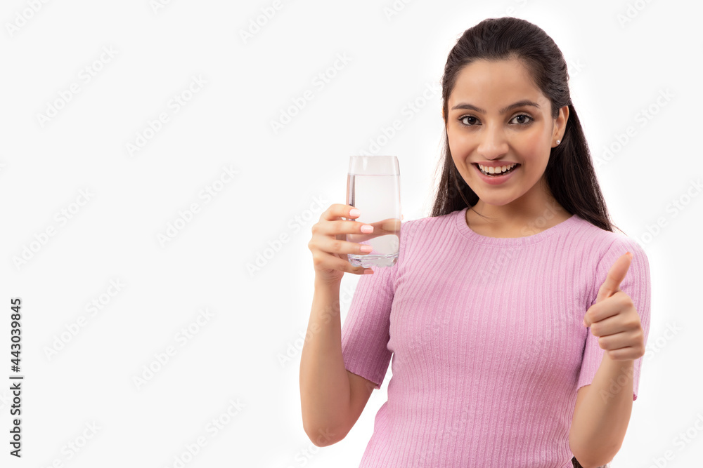 A TEENAGER POSING IN FRONT OF CAMERA HOLDING A GLASS OF WATER A TEENAGER POSING IN FRONT OF CAMERA HOLDING A GLASS OF WATER