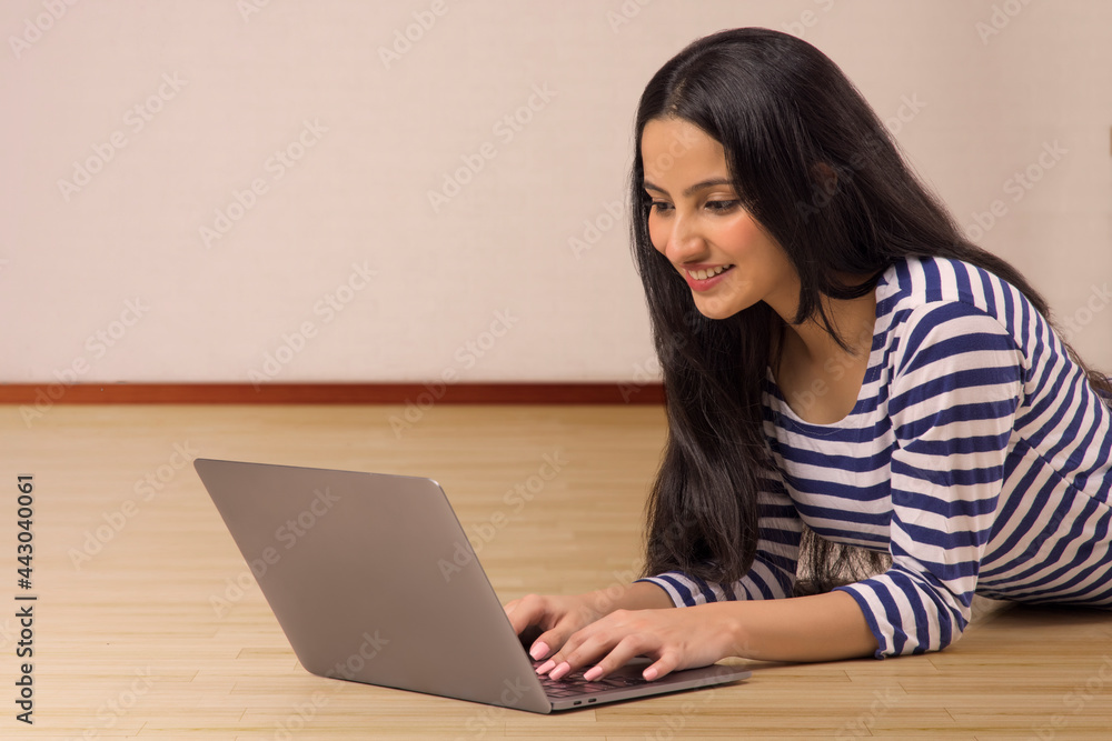 A TEENAGE GIRL RESTING ON FLOOR AND USING LAPTOP A TEENAGE GIRL RESTING ON FLOOR AND USING LAPTOP