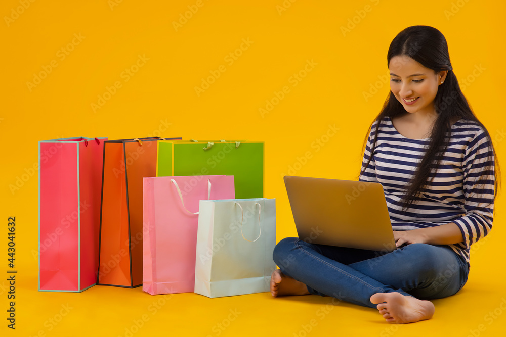 A young woman working on laptop with carrybags by her side. A young woman working on laptop with carrybags by her side.