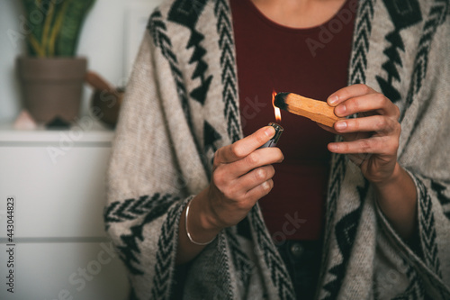 woman lighting a palo santo dressed with a handmade poncho. background with copy space. meditation concept